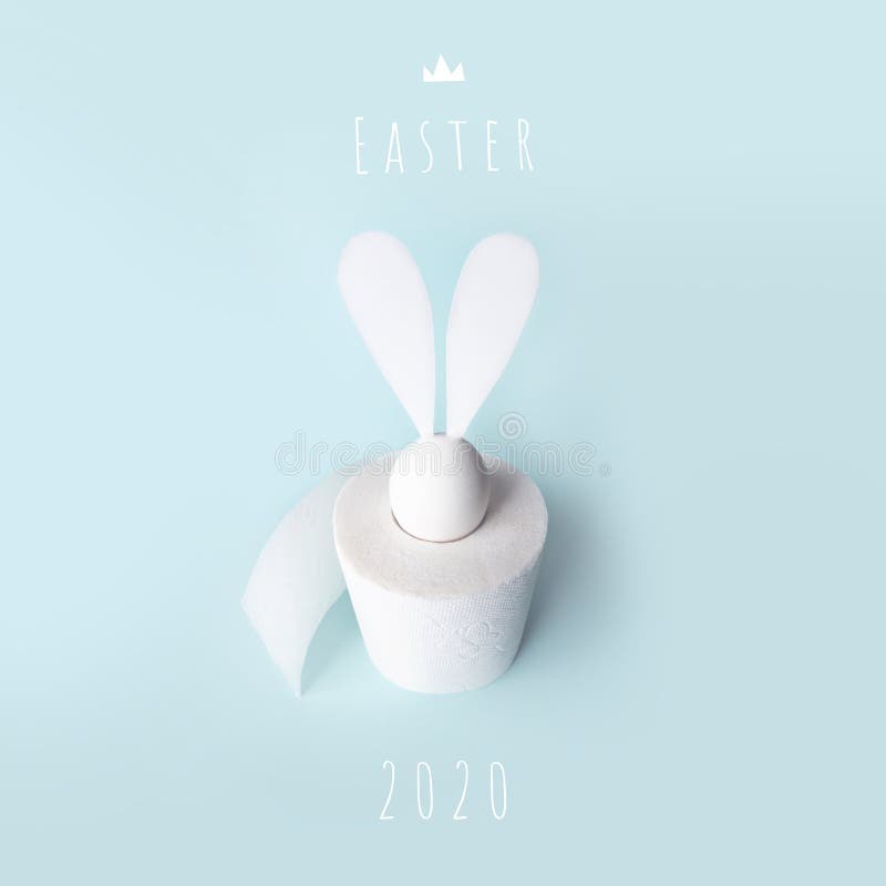 White egg with hare ears in a roll of toilet paper. Hard shadow on a light background. Concept on Easter 2020