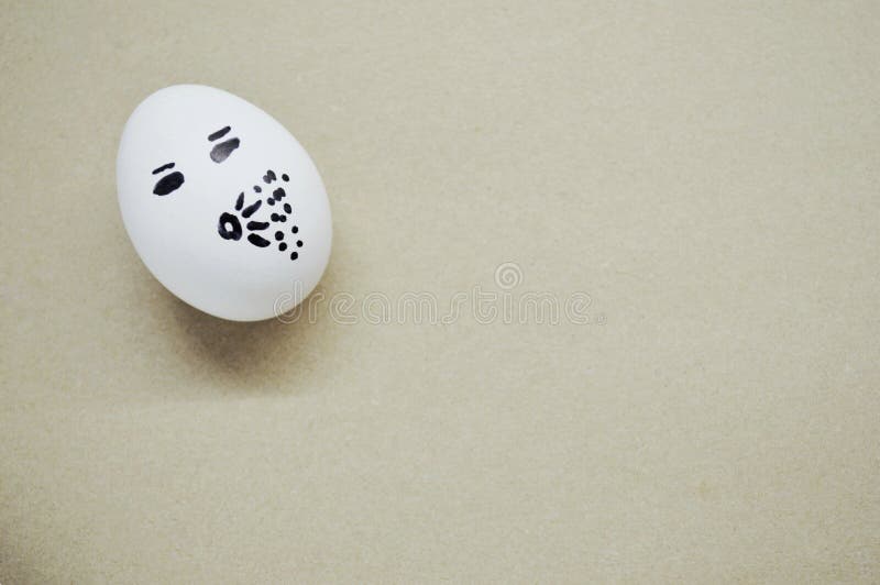 White Egg with a Painted Sneezing Face on Wooden Background Stock Photo