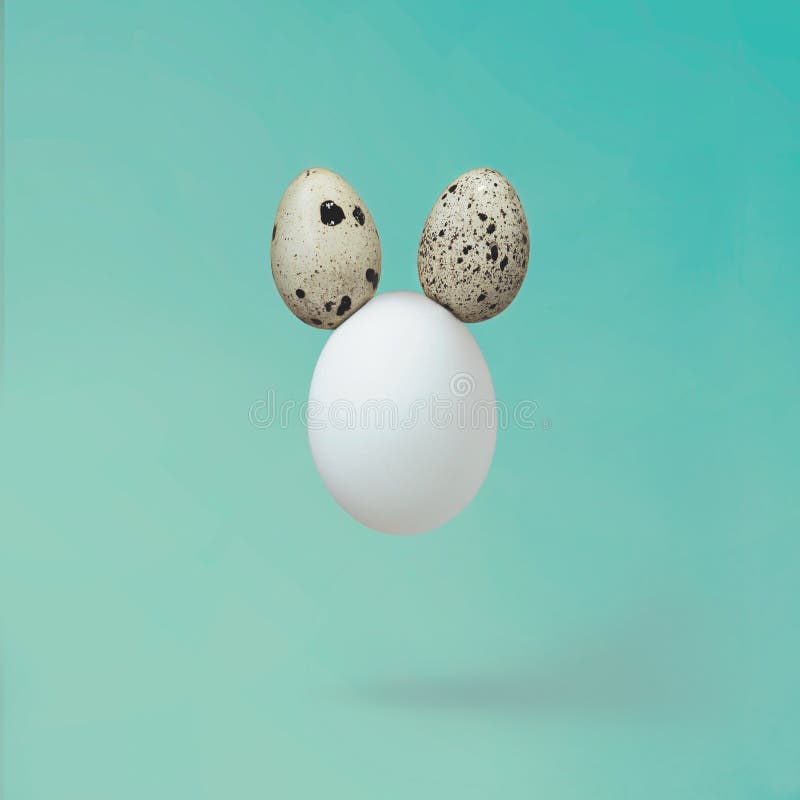 White egg with quail eggs as ears - minimal creative Easter concept stock photography