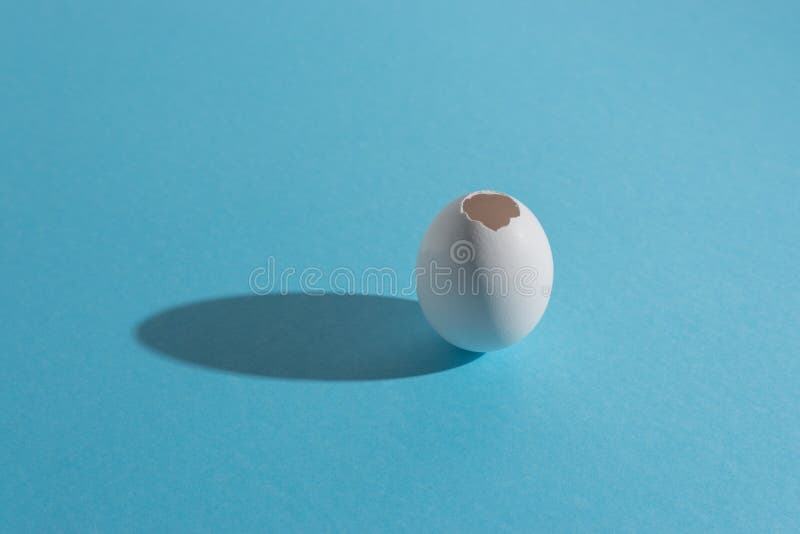 White egg shell on bright blue background. Minimal Easter concept royalty free stock photos