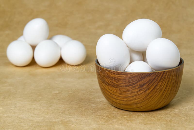 White Eggs isolated in wooden bowl on beige textured background