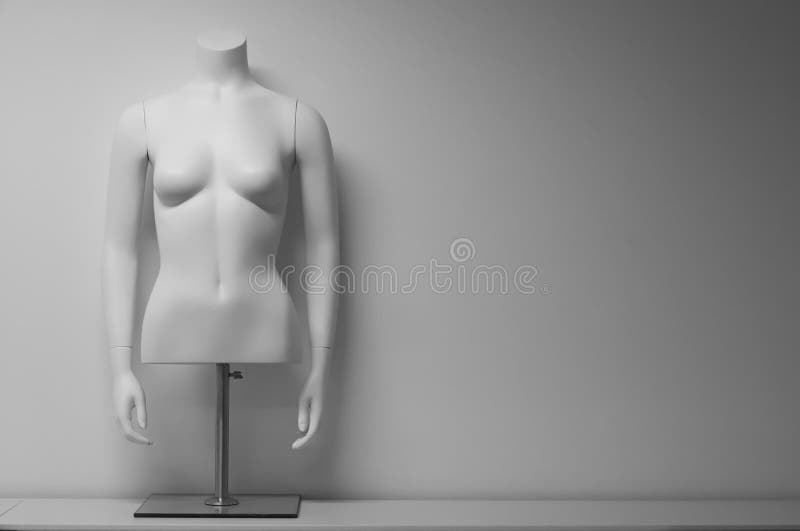 White female mannequin torso on a stand in front of white background.