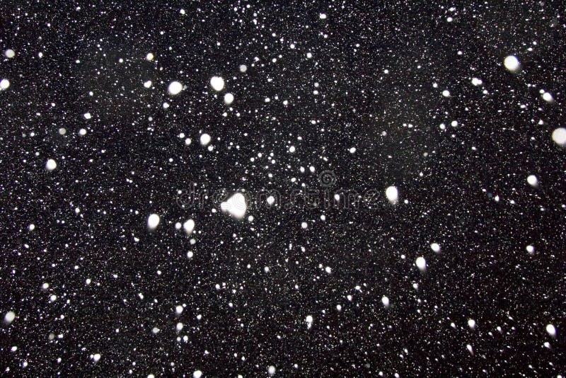 White flakes of snow on a black background.