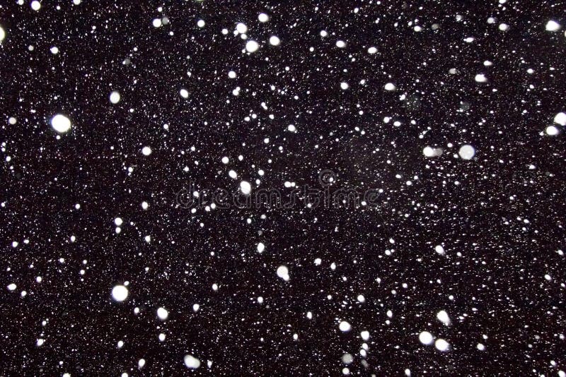 White flakes of snow on a black background.