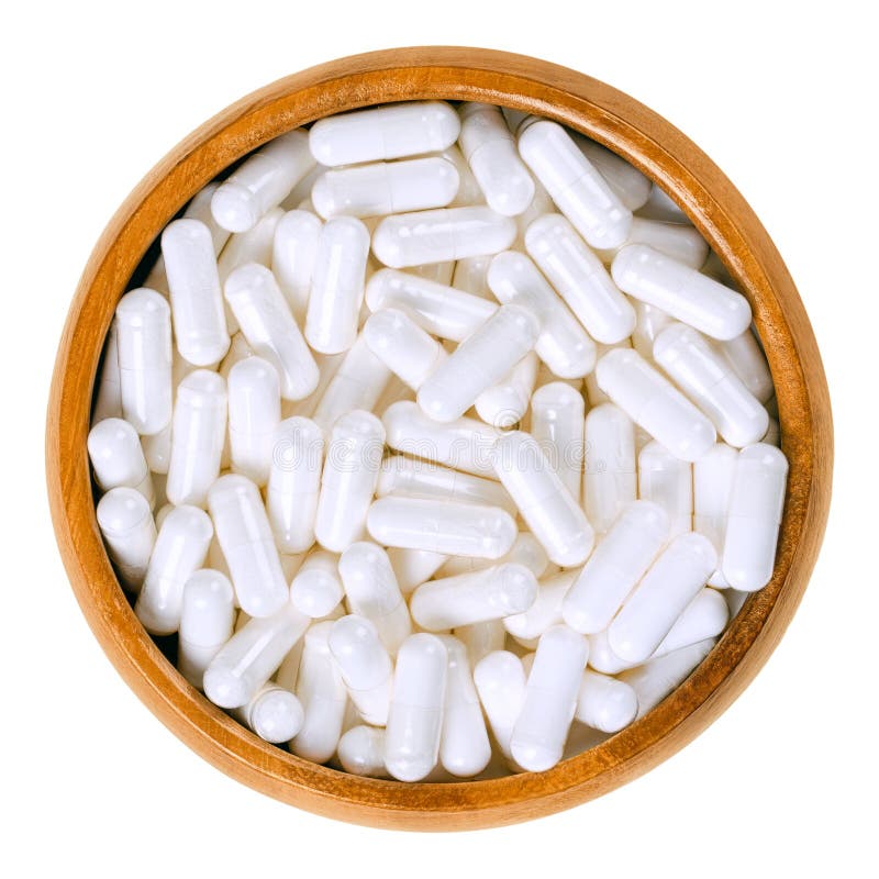 White food supplement capsules in wooden bowl over white