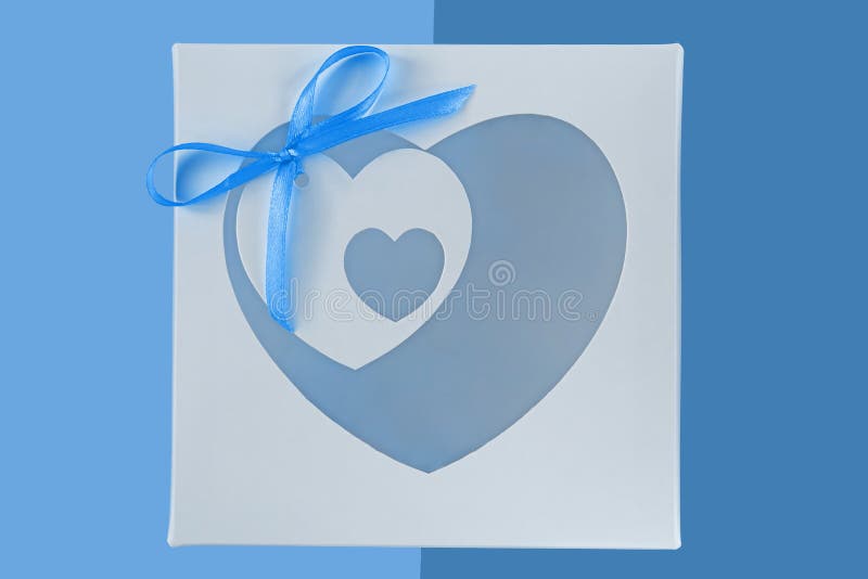 White gift box with heartshaped window and card tag on pastel blue background flatlay, creative minimal concept stock photography White gift box with heartshaped window and card tag on pastel blue background flatlay, creative minimal concept stock photography
