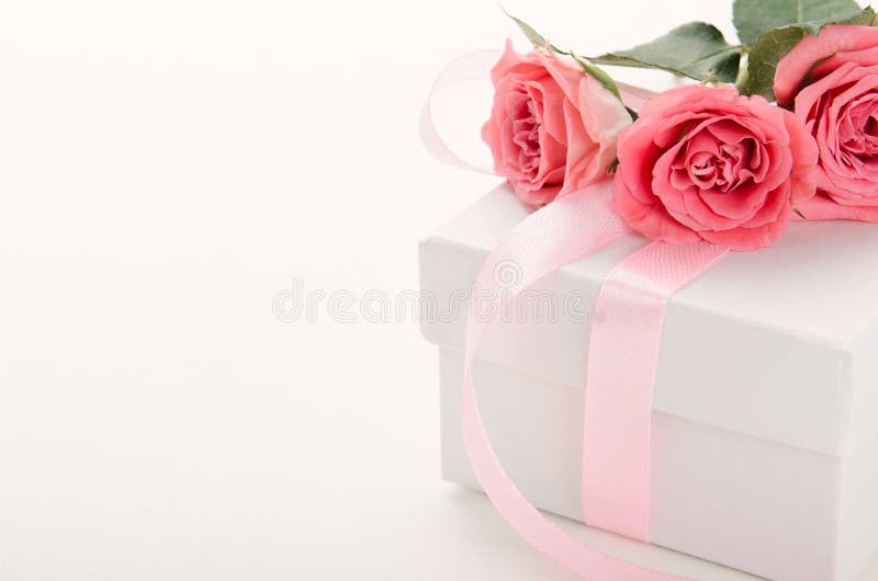 White gift box with pink ribbon and roses on white background. A gift for Valentine`s Day, birthday, women`s day. Copy