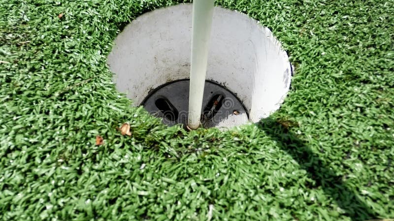 White golf ball rolling in the cup on artificial putting green