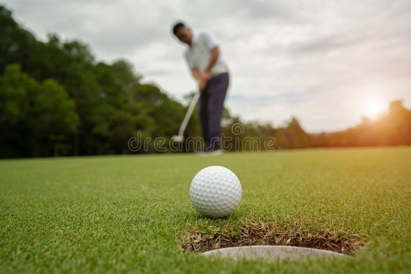 White Golf Ball Rolling Down Golf Hole on Putting Green with Evening