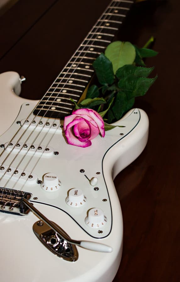 White guitar with a pink rose on the side of soundboard