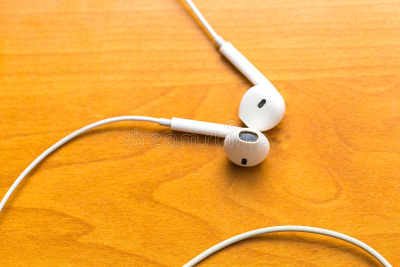 White headphones lying on wooden table stock photography