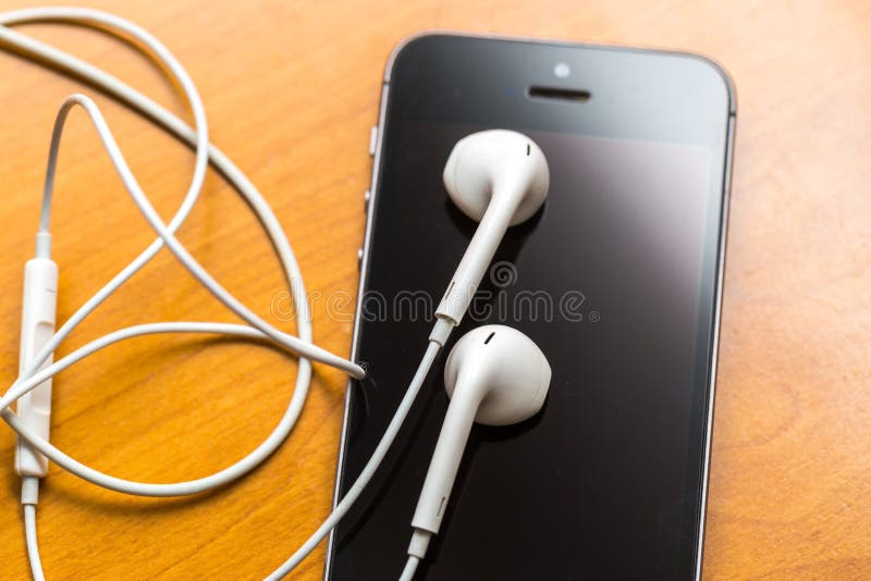White headphones lying on wooden table stock photo