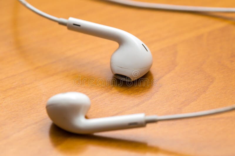White headphones lying on wooden table stock photography