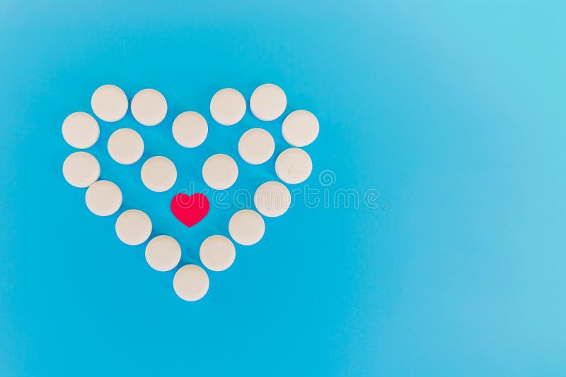 The white heart pills on a blue background with copy space