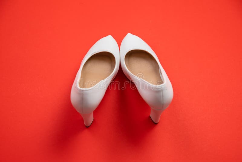 White high heeled shoes on red background - top view concept - heels pigeon toe stock image White high heeled shoes on red background - top view concept - heels pigeon toe stock image