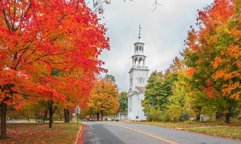 White historical church in Vermont surrounded by autumn colorful trees