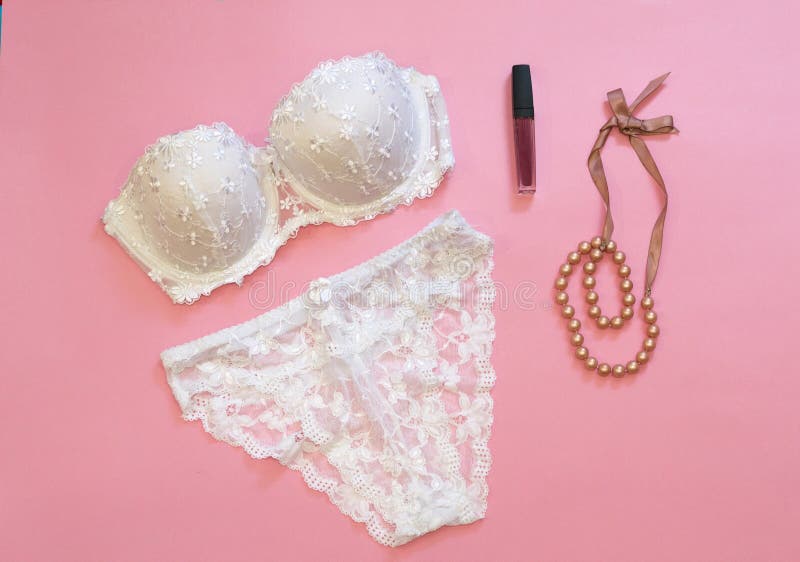 White lacery lingerie near lipstick and necklace on pink background. Woman underwear for special occasions. Composition for beauty royalty free stock image White lacery lingerie near lipstick and necklace on pink background. Woman underwear for special occasions. Composition for beauty royalty free stock image