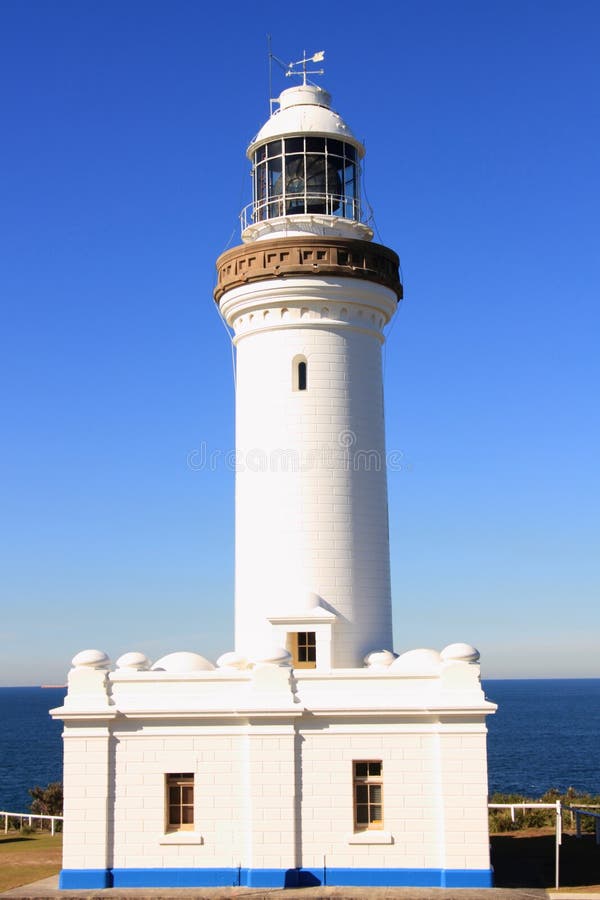 White lighthouse by blue sky and sea royalty free stock photography