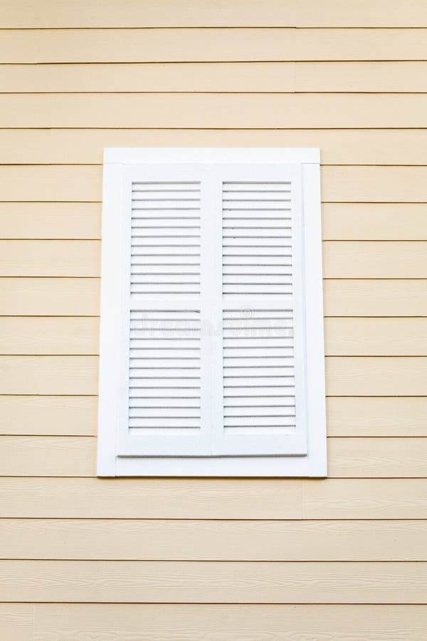 White Louvered Window Shutter on a Pink Wooden Building Stock Photo