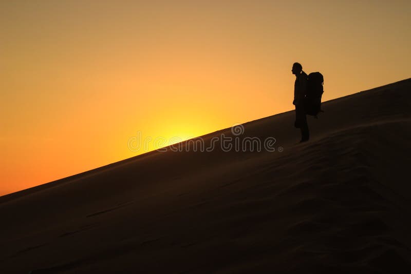 A white male traveler in sportswear with a backpack on his back is standing on the orange sand of a dune in Soususfleu National Pa stock image A white male traveler in sportswear with a backpack on his back is standing on the orange sand of a dune in Soususfleu National Pa stock image