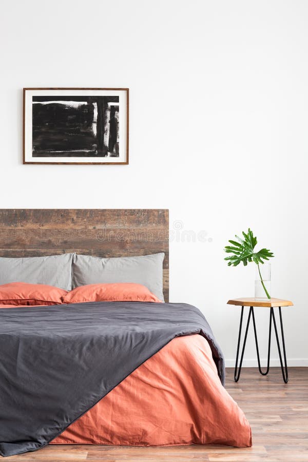 White minimal interior with simple bed, coral and grey linen bedsheets and nightstand royalty free stock photography