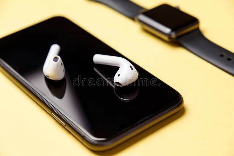 White modern wireless headphones lie on the smartphone display. Yellow background. Concept of modern technologies royalty free stock image White modern wireless headphones lie on the smartphone display. Yellow background. Concept of modern technologies royalty free stock image