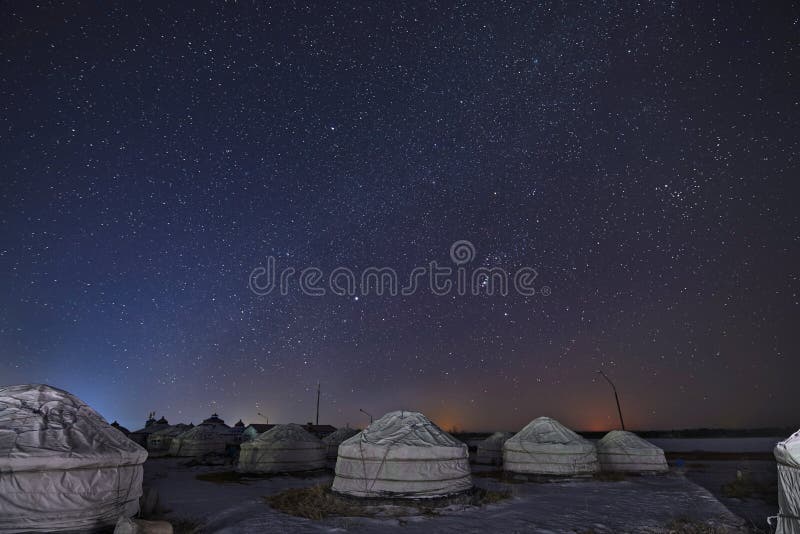 The white Mongolian yurts in starry sky in winter