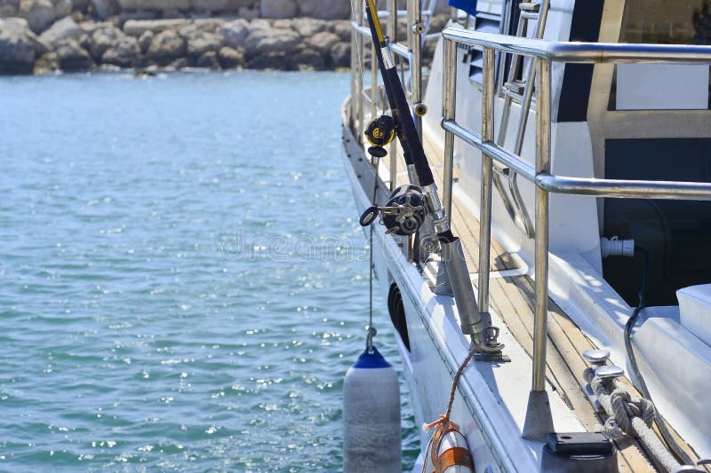 White motor yacht in the expectation of the tourists and fishermen on the pier. Trolling rods stock photo White motor yacht in the expectation of the tourists and fishermen on the pier. Trolling rods stock photo
