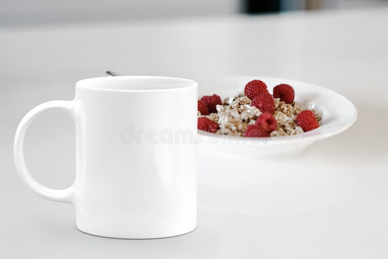 White mug next to a bowl of cereal.