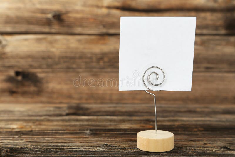 White note paper on a holder on brown wooden background. stock images