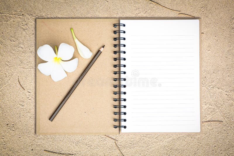 White notebook with frangipani flower on the sand