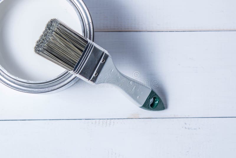 White Paint Brushes and a Can of Oil Paint on a White Wooden Table