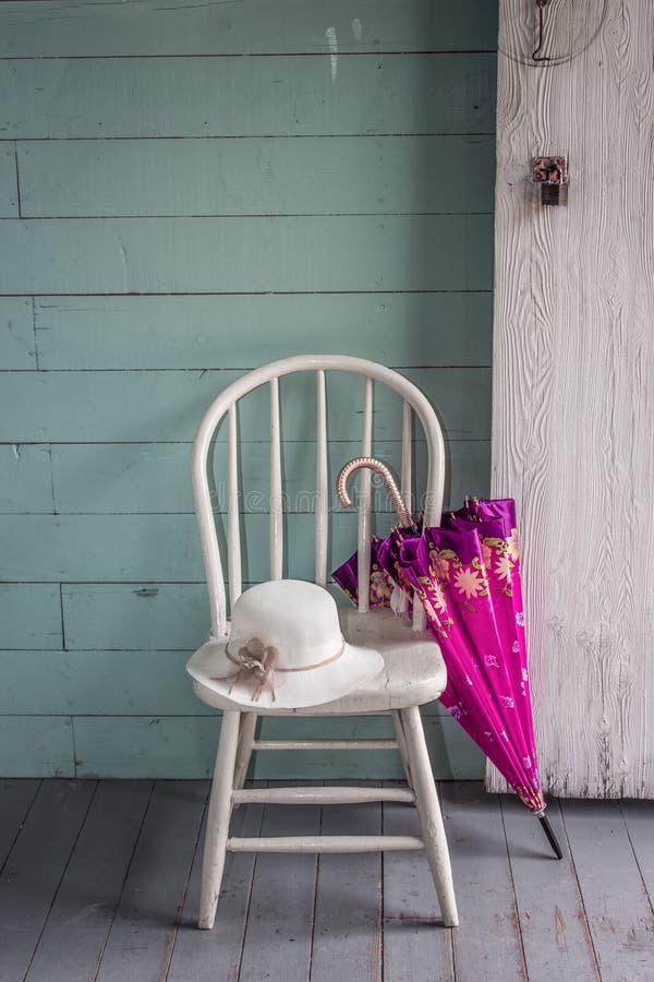 White painted chair with pink umbrella leaning against it