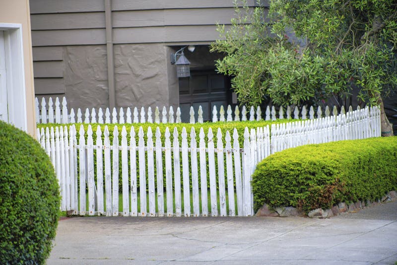 White Picket Fence in Suburban Neighborhood with Shrubs and Grass in ...