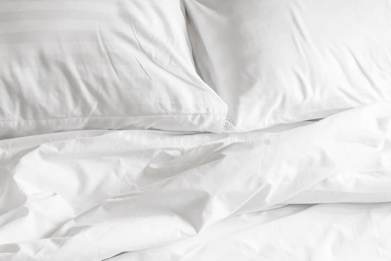 White pillow with messy messy blanket on bed in bedroom Close up of bedding sheets with copy space