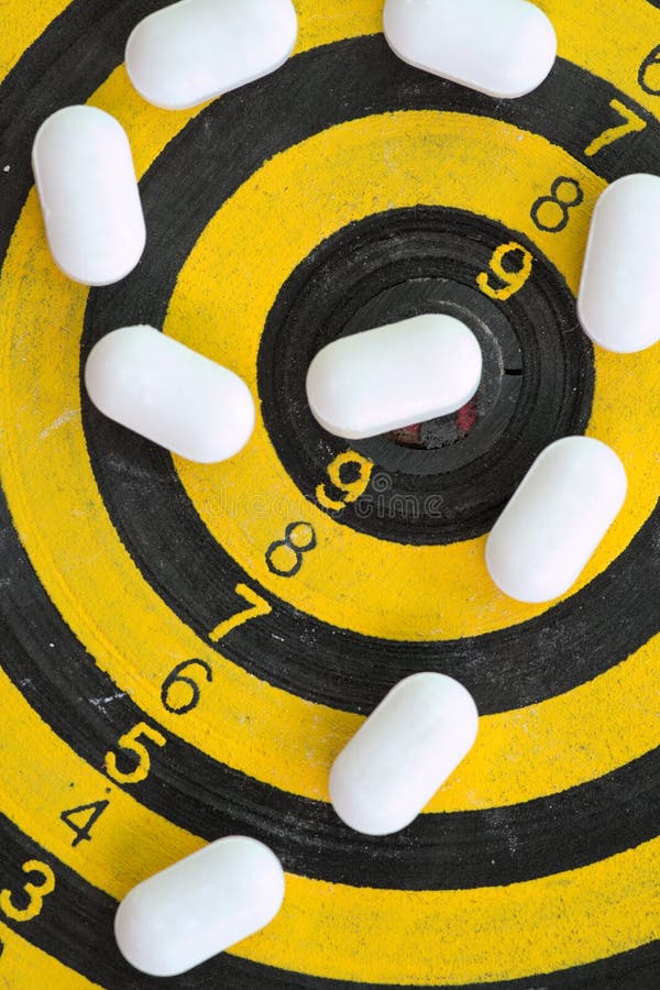 White pills on yellow and black dart target stock photos