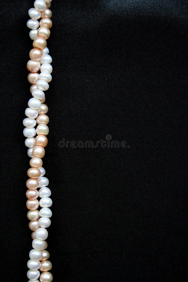 White and pink pearls on the black silk background royalty free stock photos