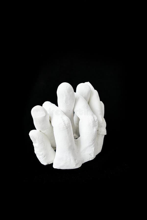 White plaster sculpture of intertwined fingers on a black background. High quality photo