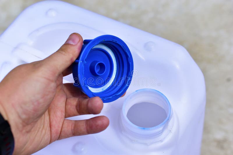 A White Plastic Canister with a Blue Lid in the Hands of a Man Stock Photo Image of household