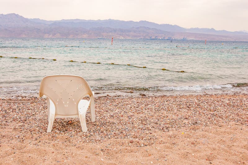 White plastic chair standing on the pebbles stones beach on Red Sea in Eilat