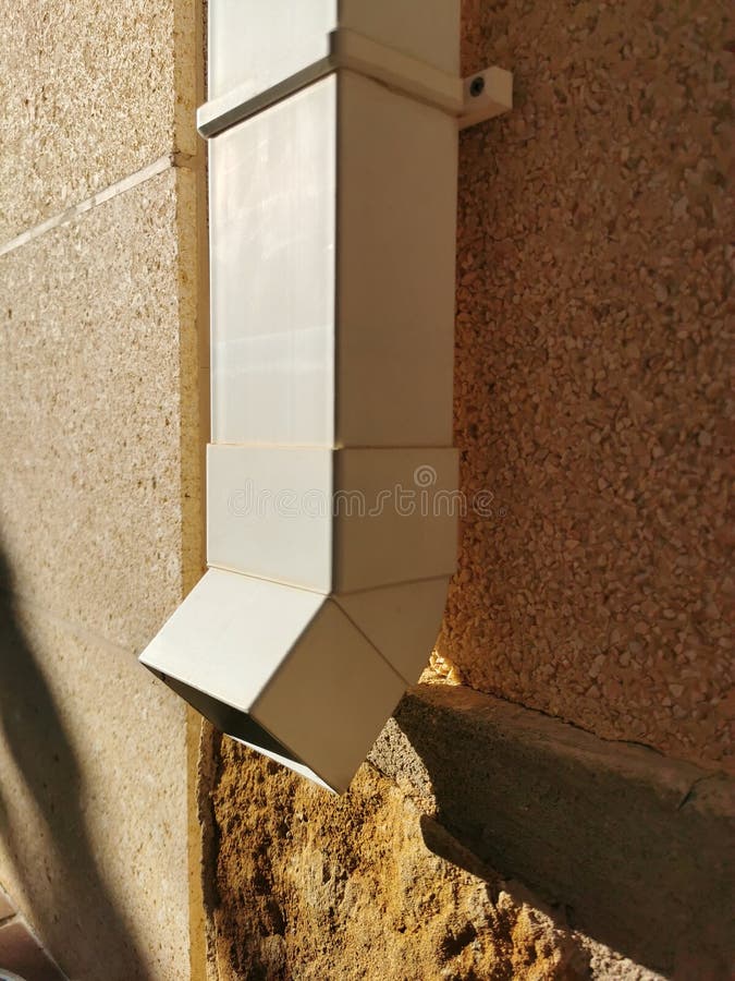 White Plastic Drain Pipe on the Brown Brick Wall. Downspout Stock Image