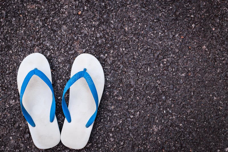 White plastic flip flop shoe on black asphalt road