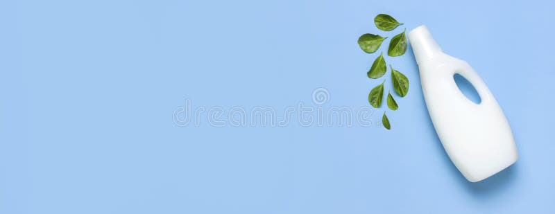 White plastic packaging of laundry detergent, liquid powder, washing conditioner, green leaves on blue background. Flat lay top