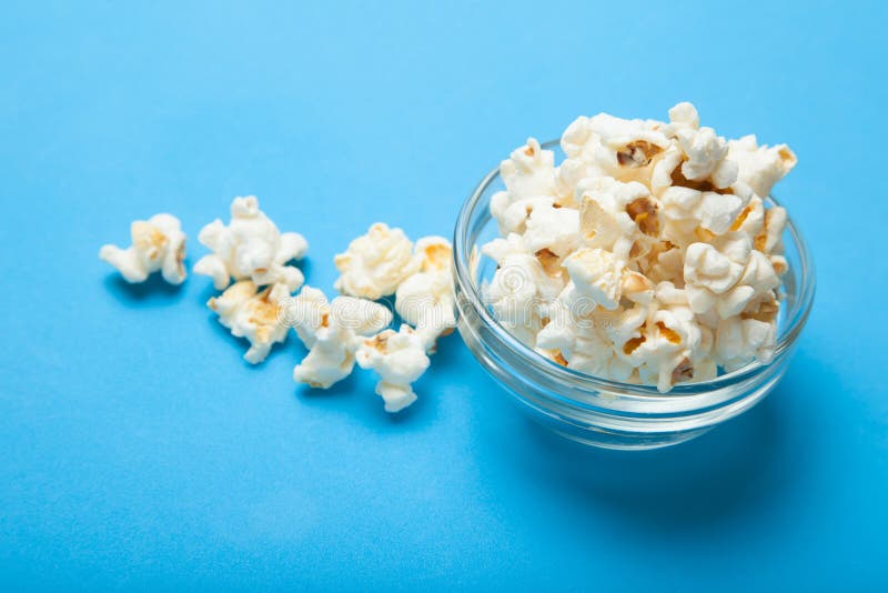 White popcorn in a glass bowl on a blue background vector illustration White popcorn in a glass bowl on a blue background vector illustration