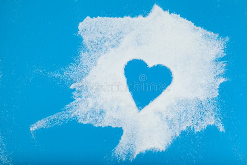 White powder is chaotically scattered on blue surface. Empty space in the form of heart. Collagen or protein. Healthy food
