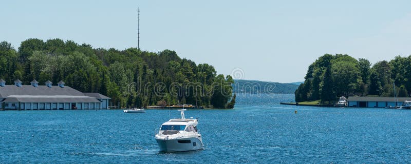 White power boat and boathouses in panoramic format. White power boat and boathouses on Lake Charlevoix in Upper Michigan royalty free stock photos White power boat and boathouses in panoramic format. White power boat and boathouses on Lake Charlevoix in Upper Michigan royalty free stock photos