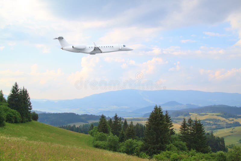 White private jet business jet flies against backdrop of  summer forrest, meadows and fields countryside landscape in Slovakia