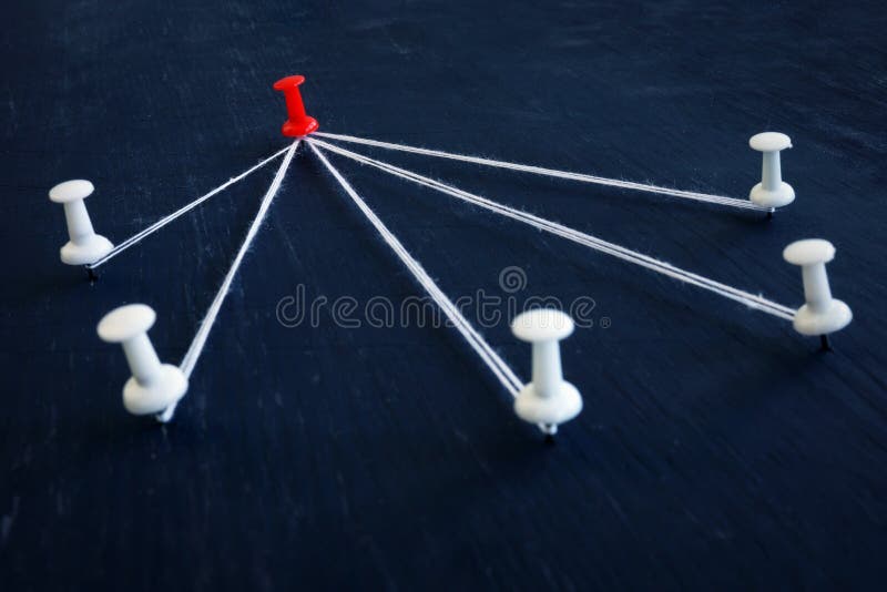 White push pins and red one connected by thread. Leadership, management and delegating