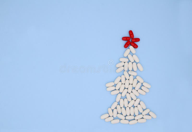White, Red Medical Pills in Form of Christmas Tree on Blue Background with Copy Space. Christmas