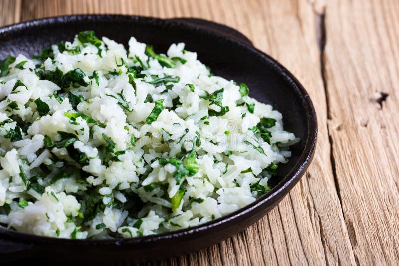 White rice with spinach, plant based meal. White rice with spinach served in cast iron skillet on rustic wooden table with fresh green leaf vegetables, plant royalty free stock images White rice with spinach, plant based meal. White rice with spinach served in cast iron skillet on rustic wooden table with fresh green leaf vegetables, plant royalty free stock images
